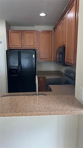 a kitchen with granite countertop wooden cabinets a refrigerator and granite counter tops