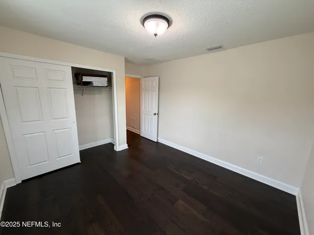 an empty room with wooden floor and cabinet