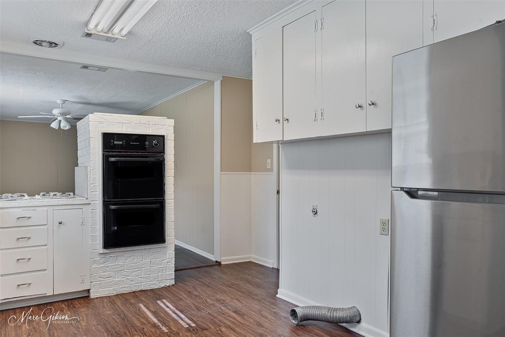 9342 Dean Road Shreveport, LA 71118 - Photo 8 of 18 Kitchen featuring wood-finish flooring, white cabinetry, a built-in double oven, a gas range with white countertops, and a stainless steel refrigerator