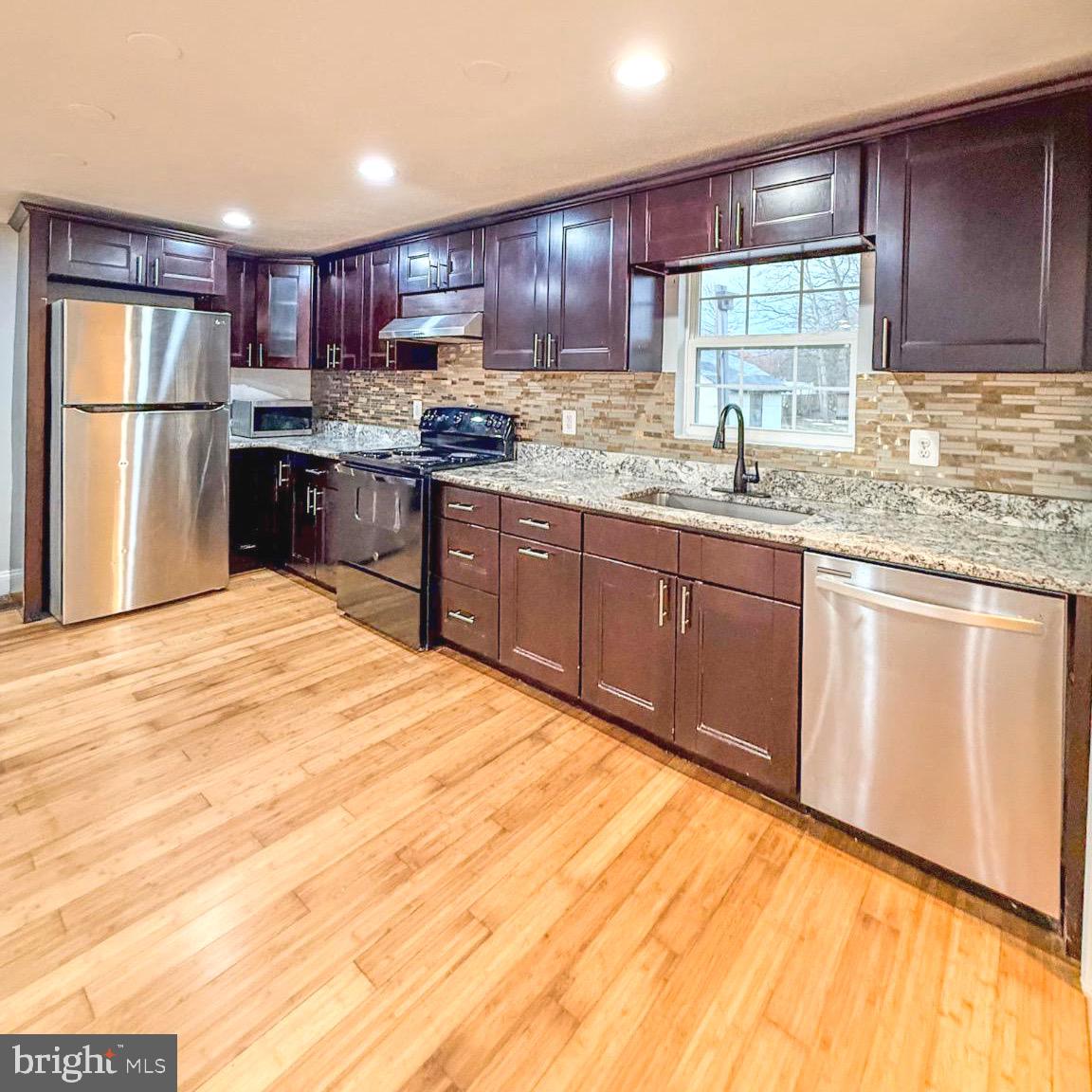 205 Biddle Road Accokeek, MD 20607 - Photo 19 of 31 a kitchen with granite countertop wooden cabinets stainless steel appliances and a window