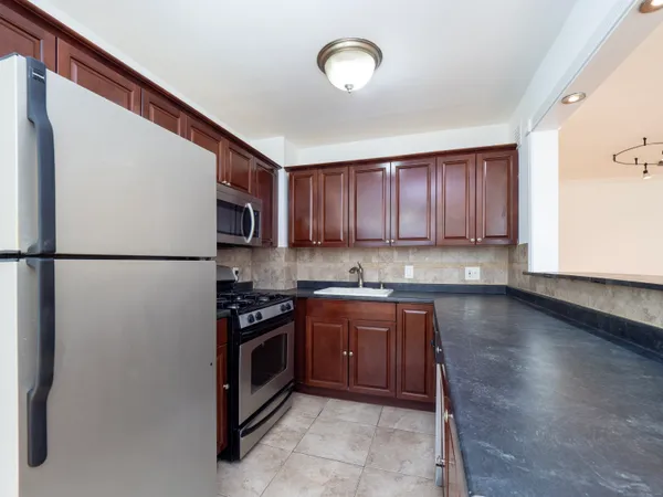 a kitchen with stainless steel appliances granite countertop a refrigerator a stove a sink and a microwave