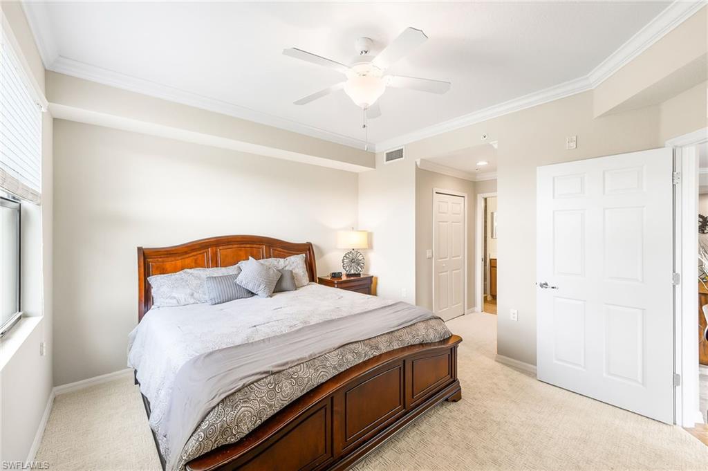 9727 Acqua Court, Unit 421 Naples, FL 34113 - Photo 16 of 35 a bedroom with a large bed and a chandelier fan