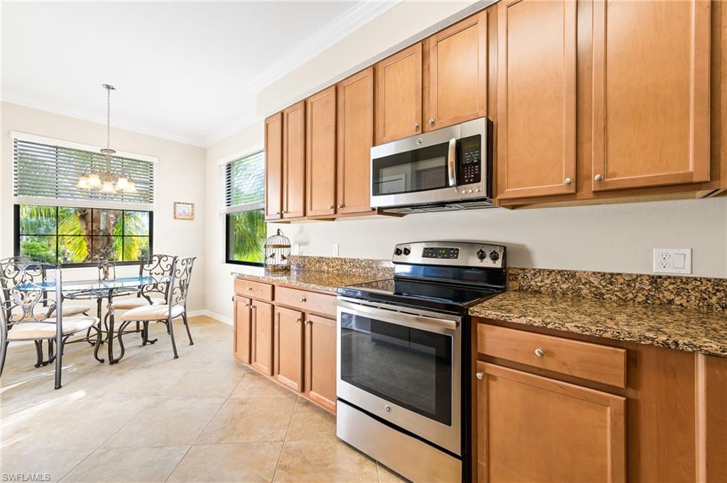 9727 Acqua Court, Unit 421 Naples, FL 34113 - Photo 9 of 35 a kitchen with stainless steel appliances granite countertop a stove a sink and a microwave