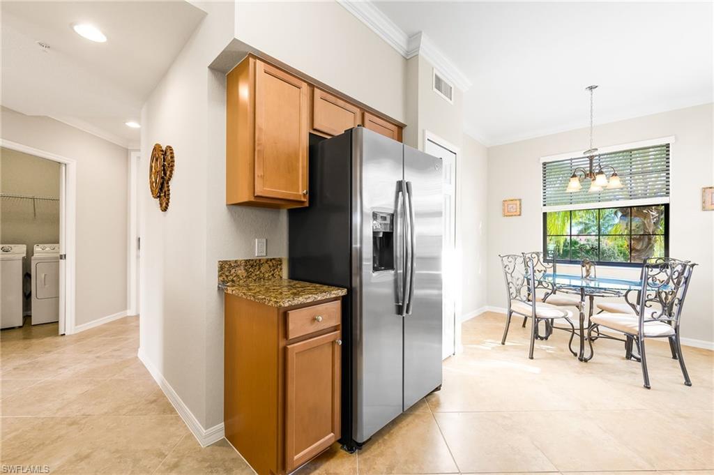 9727 Acqua Court, Unit 421 Naples, FL 34113 - Photo 10 of 35 a kitchen with stainless steel appliances granite countertop a refrigerator a stove and a dining table with wooden floor