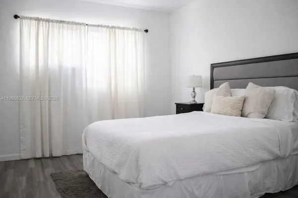 a large white bed in a bedroom next to a window