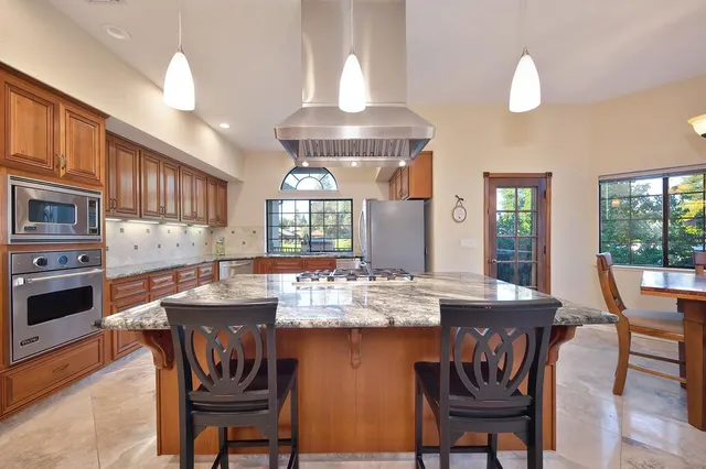 a kitchen with kitchen island granite countertop a stove cabinets and refrigerator