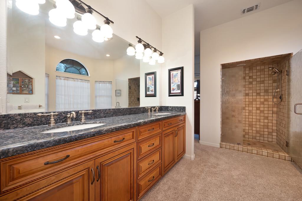 14965 Anillo Way Rancho Murieta, CA 95683 - Photo 29 of 59 a spacious bathroom with a granite countertop sink a mirror and a shower