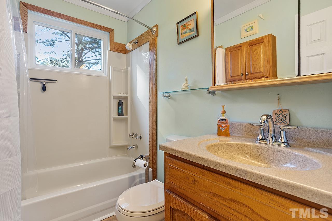 2820 Willow Court Raleigh, NC 27610 - Photo 22 of 33 a bathroom with a granite countertop sink a mirror a bathtub and shower