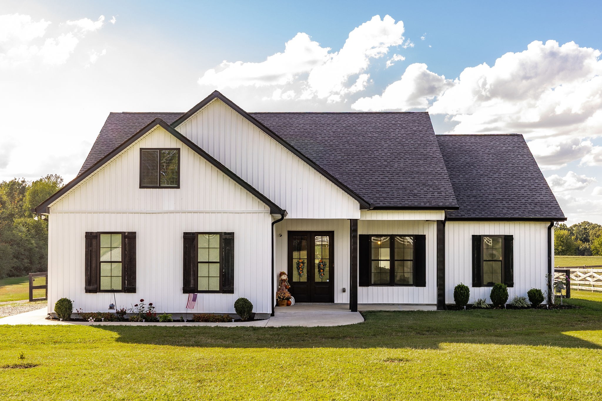 a view of a white house with a large pool lawn chairs and a yard with plants