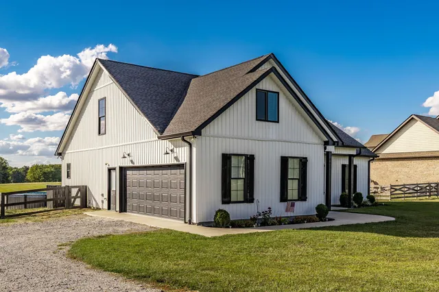 a view of a white house with a big yard and potted plants