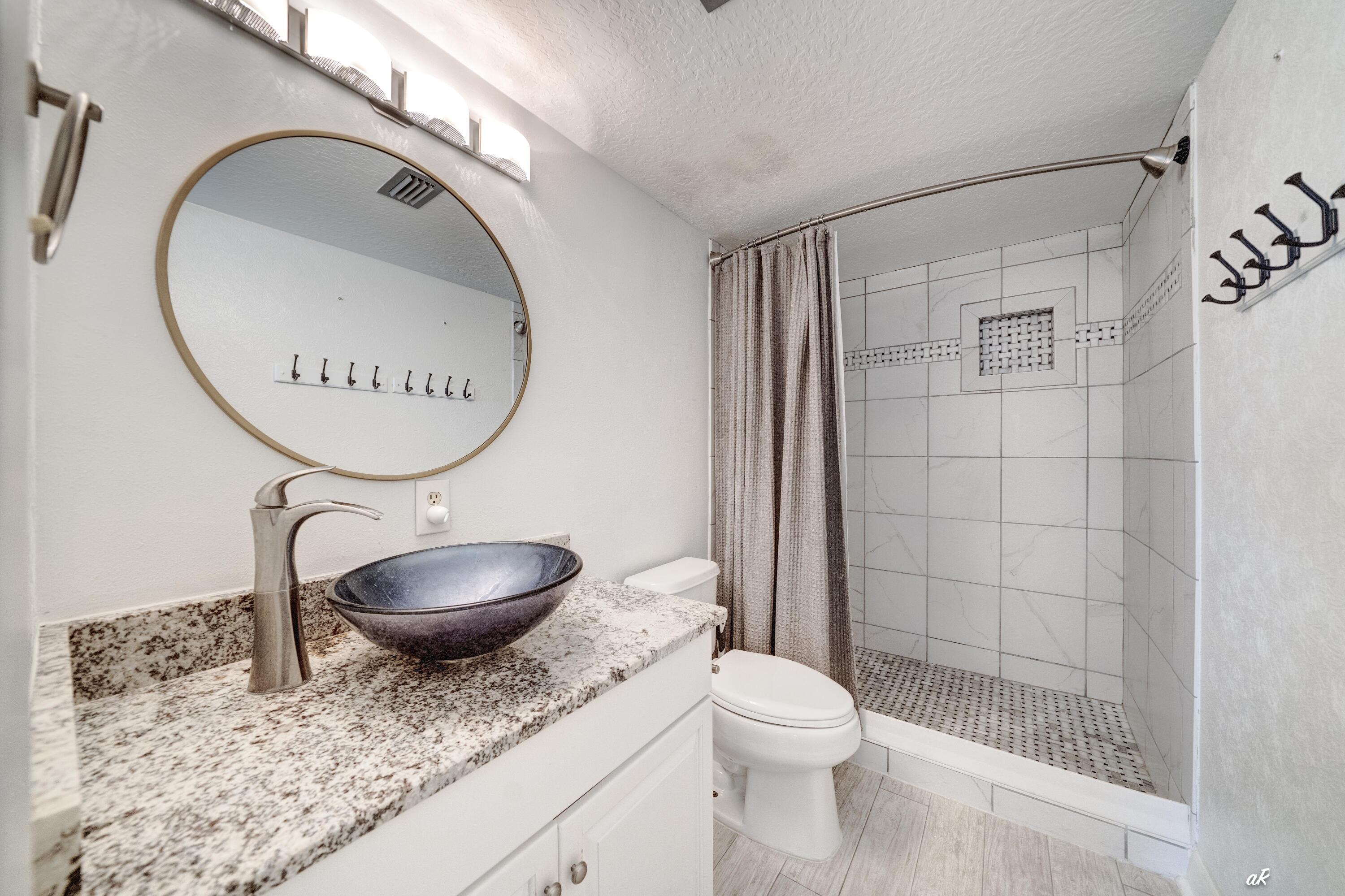30 Moreno Point Road, Unit 404A Destin, FL 32541 - Photo 21 of 52 a bathroom with a granite countertop toilet sink mirror and vanity