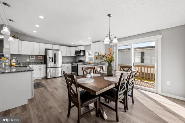 a view of a dining room and livingroom with furniture wooden floor a chandelier