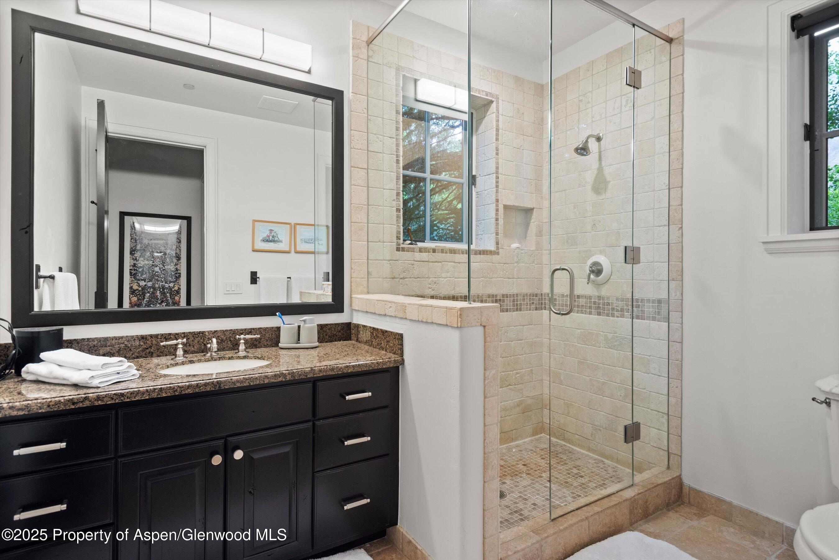 289 Exhibition Lane Aspen, CO 81611 - Photo 45 of 46 a bathroom with a granite countertop sink a mirror a shower and a bathtub