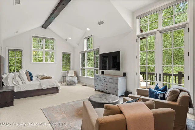a living room with furniture large windows and flat screen tv
