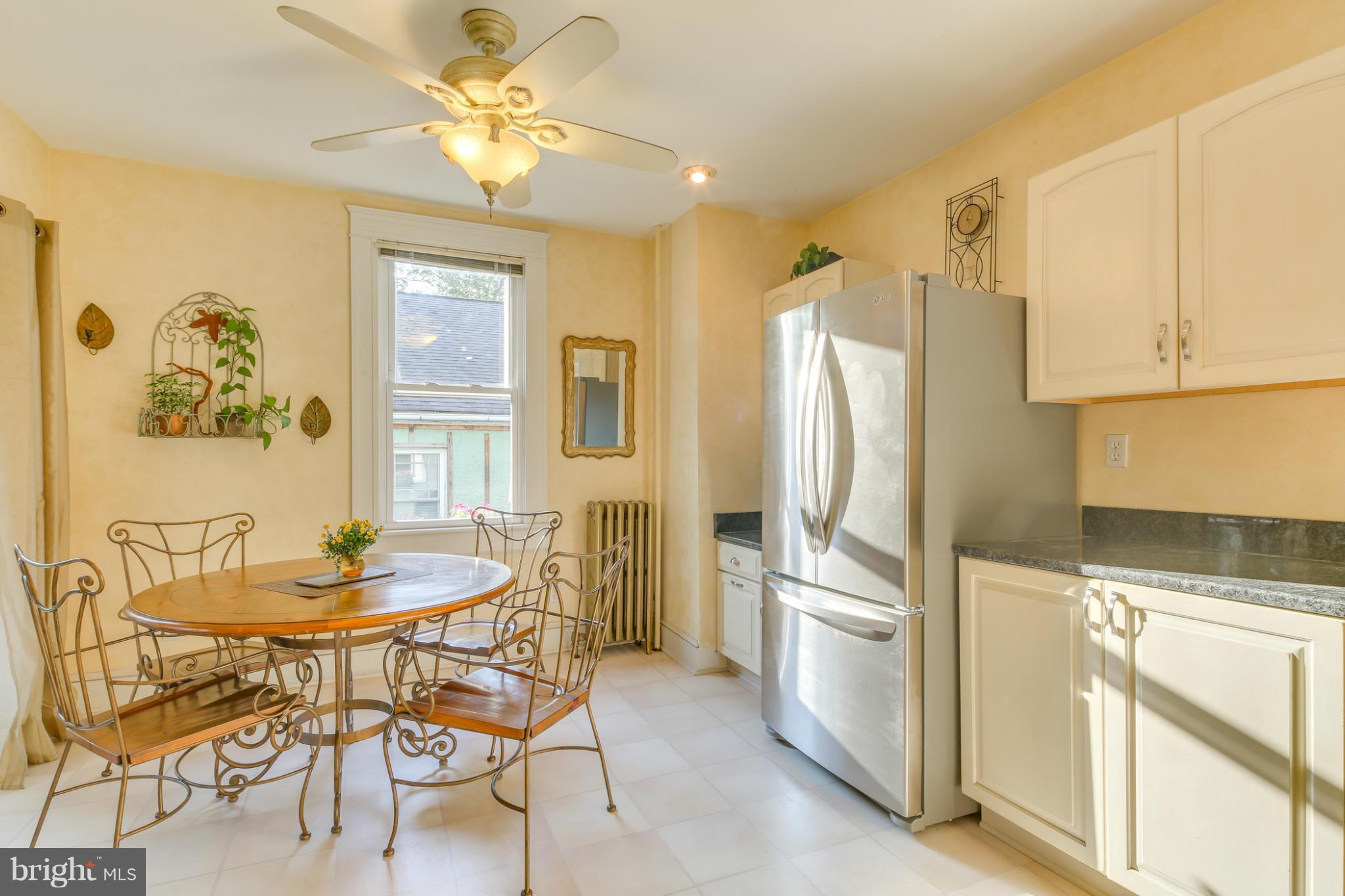 1313 Asbury Road Baltimore, MD 21209 - Photo 9 of 30 a kitchen with stainless steel appliances a refrigerator a stove a dining table and chairs