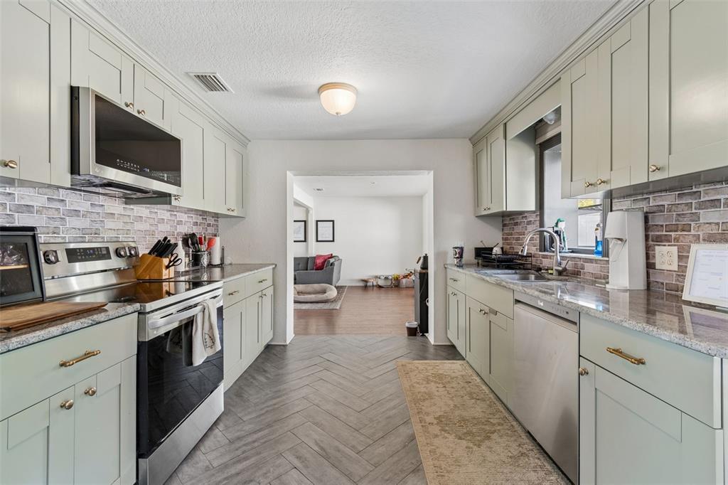 2301 West Eldred Drive Tampa, FL 33603 - Photo 7 of 34 a kitchen with stainless steel appliances granite countertop a sink and dishwasher a stove top oven with wooden floor