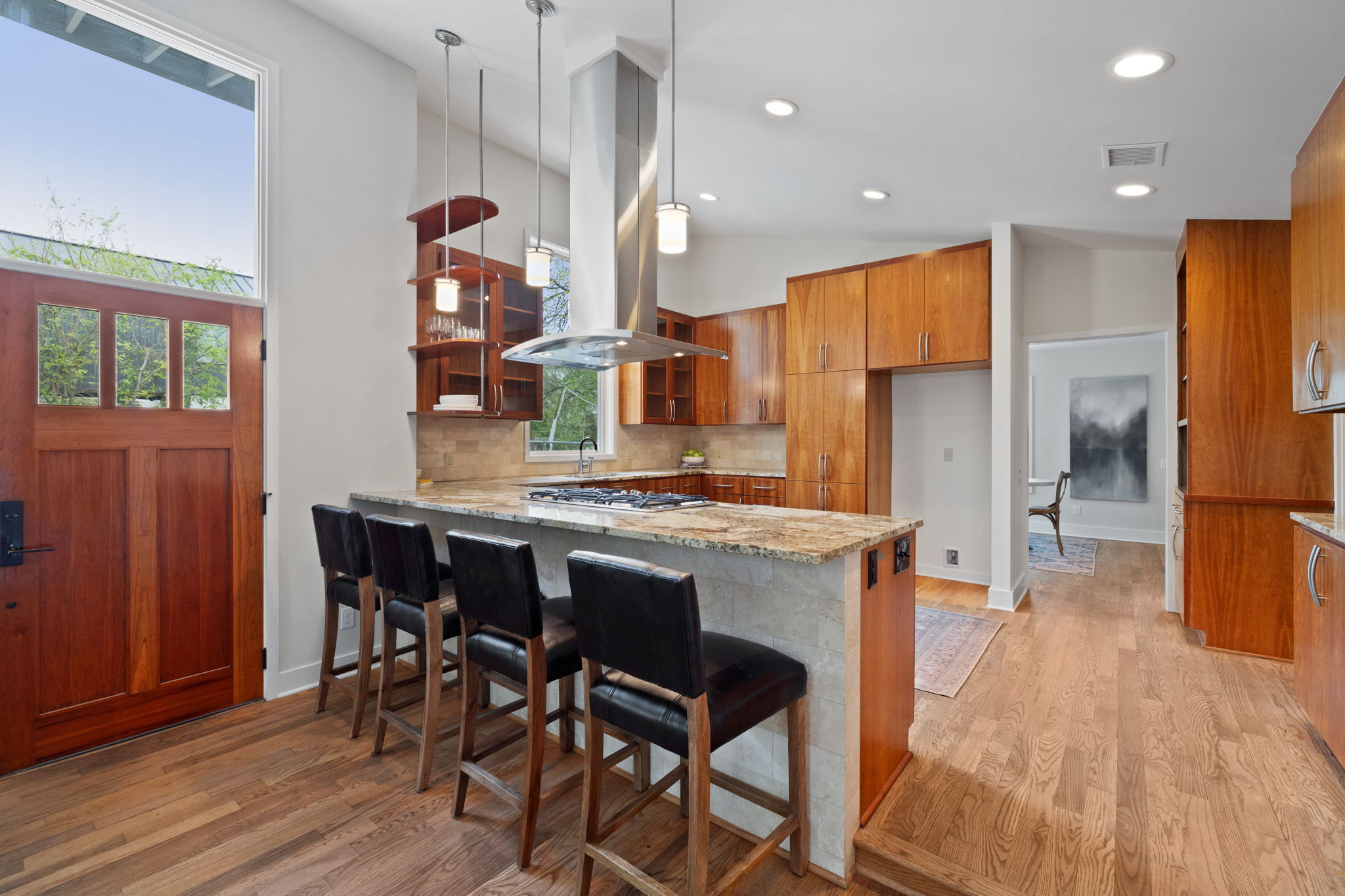 2300 South 3rd Street Austin, TX 78704 - Photo 11 of 39 Kitchen featuring light stone counters, a peninsula, brown cabinetry, island exhaust hood, and light wood-style floors