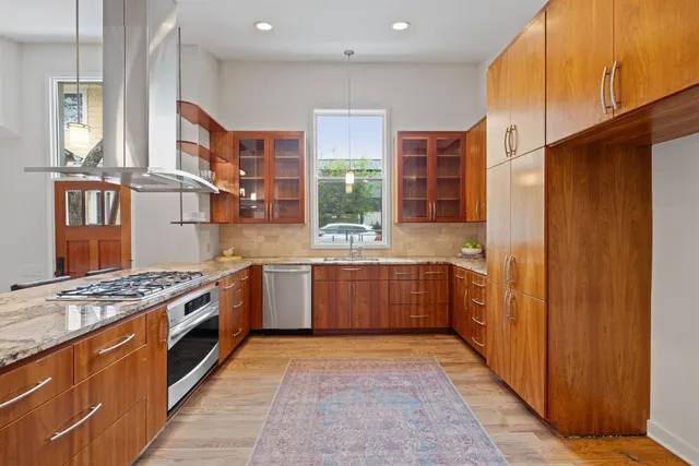 a large kitchen with stainless steel appliances granite countertop a large counter top a stove a sink and a refrigerator