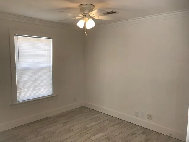 an empty room with a window and a fan