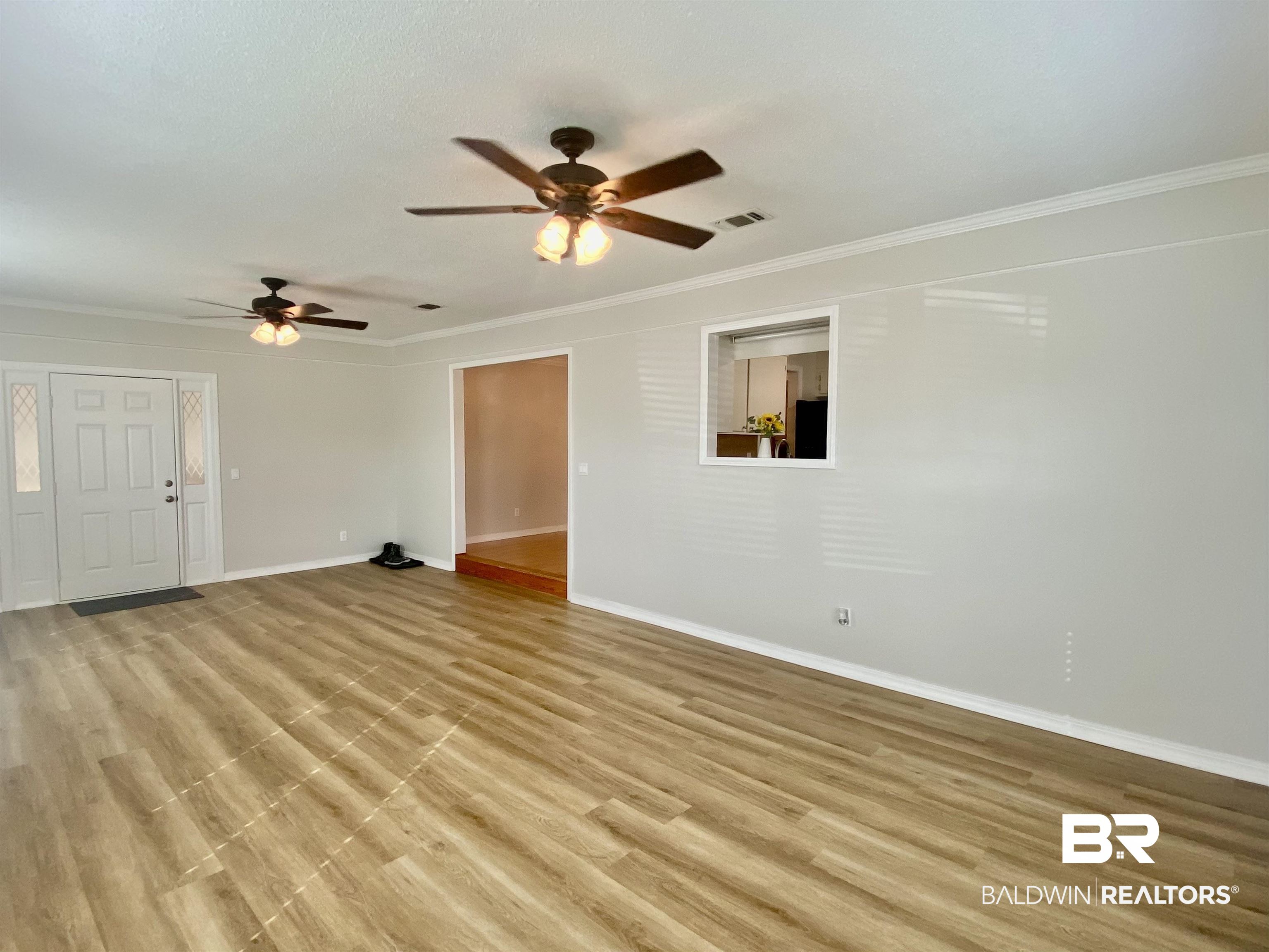 265 Azalea Drive Monroeville, AL 36460 - Photo 16 of 39 Unfurnished living room with light hardwood / wood-style floors, ceiling fan, and crown molding