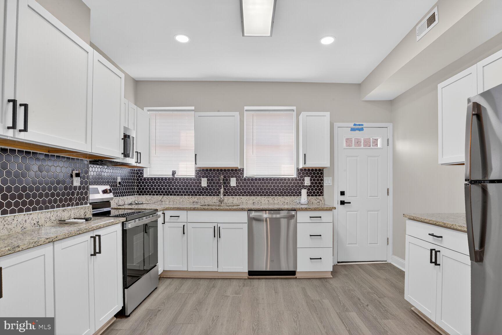 1106 South Carey Street Baltimore, MD 21223 - Photo 8 of 24 a kitchen with white cabinets stainless steel appliances and sink