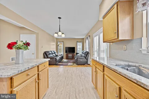 a view of a kitchen with kitchen island a stove a sink dishwasher a oven with a dining table and chairs