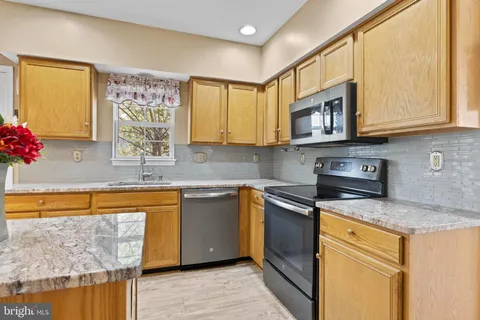 a living room with stainless steel appliances furniture a couch and a kitchen view