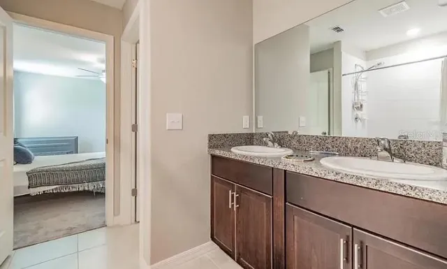 a en suite bathroom with a granite countertop sink and a mirror