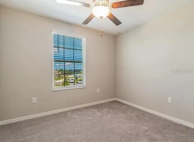 an empty room with a window and a fan