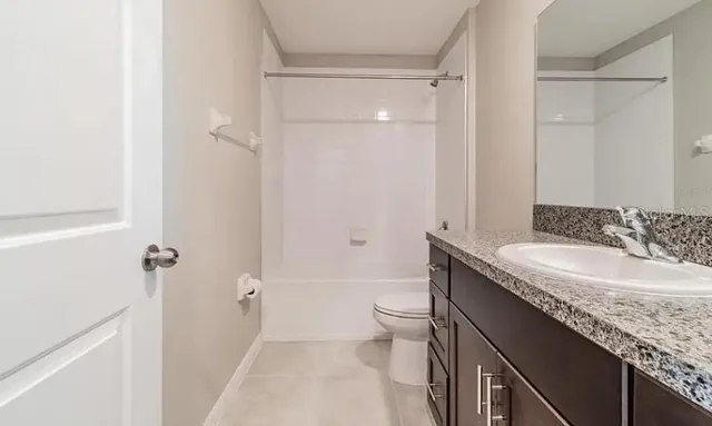a bathroom with a granite countertop sink a toilet and shower