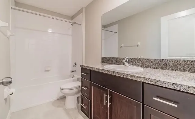 a bathroom with a granite countertop sink a toilet and shower