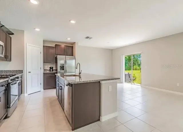 a kitchen with stainless steel appliances a stove a sink a counter top space cabinets and a window