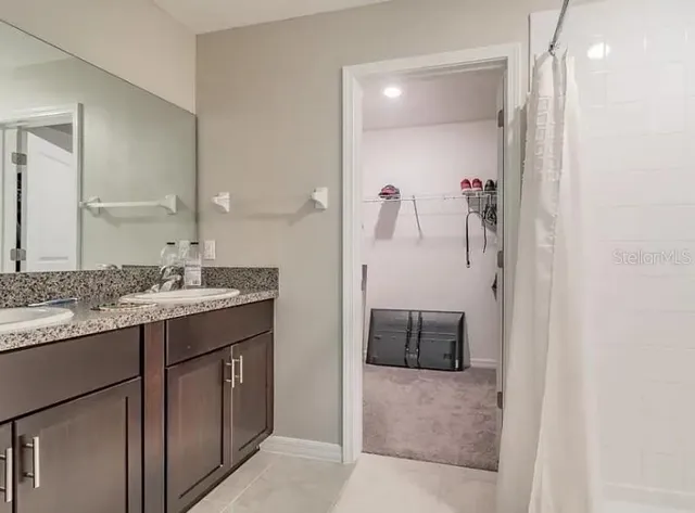 a en suite bathroom with a granite countertop sink and a mirror