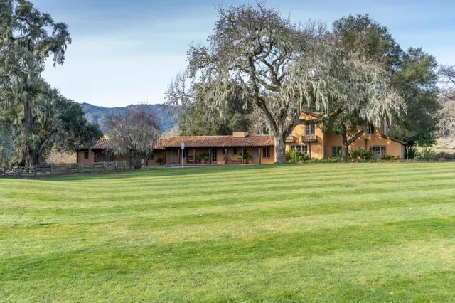 a view of a house next to a big yard with large trees