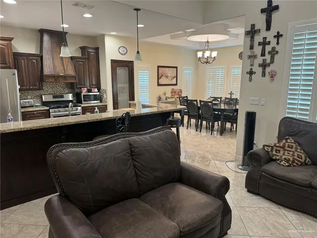 a living room with furniture kitchen view and a chandelier