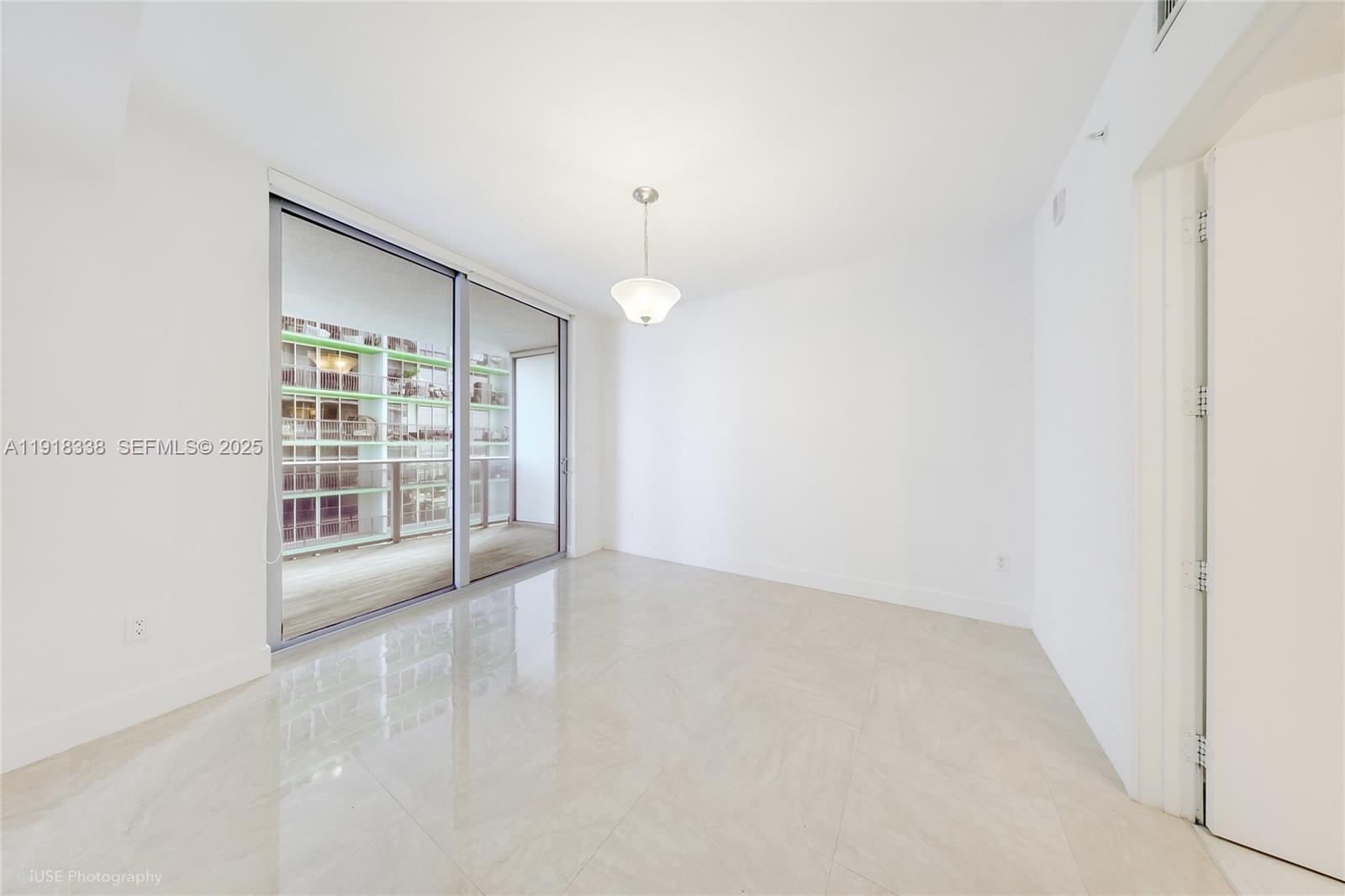 488 Northeast 18th Street, Unit 2304 Miami, FL 33132 - Photo 15 of 41 an empty room with chandelier fan and windows