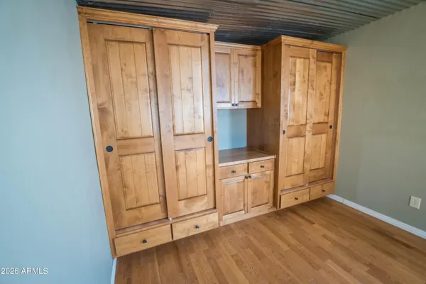 an empty room with wooden floor cabinet and windows