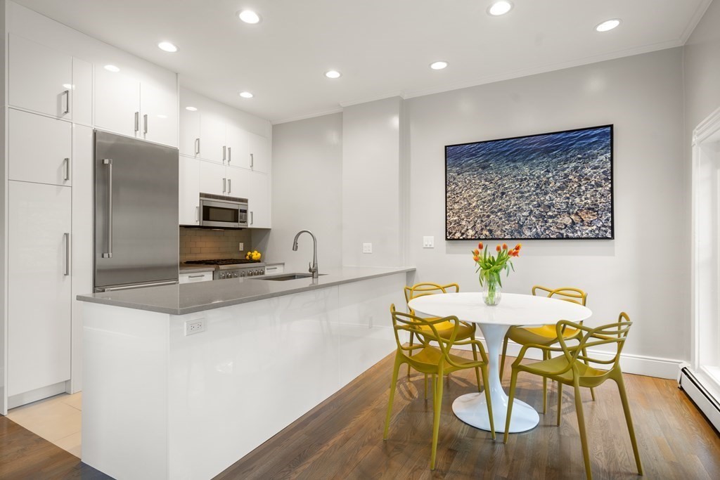 203 St Botolph Street, Unit 4 Boston, MA 02115 - Photo 2 of 26 a kitchen with stainless steel appliances kitchen island granite countertop a dining table chairs refrigerator and sink