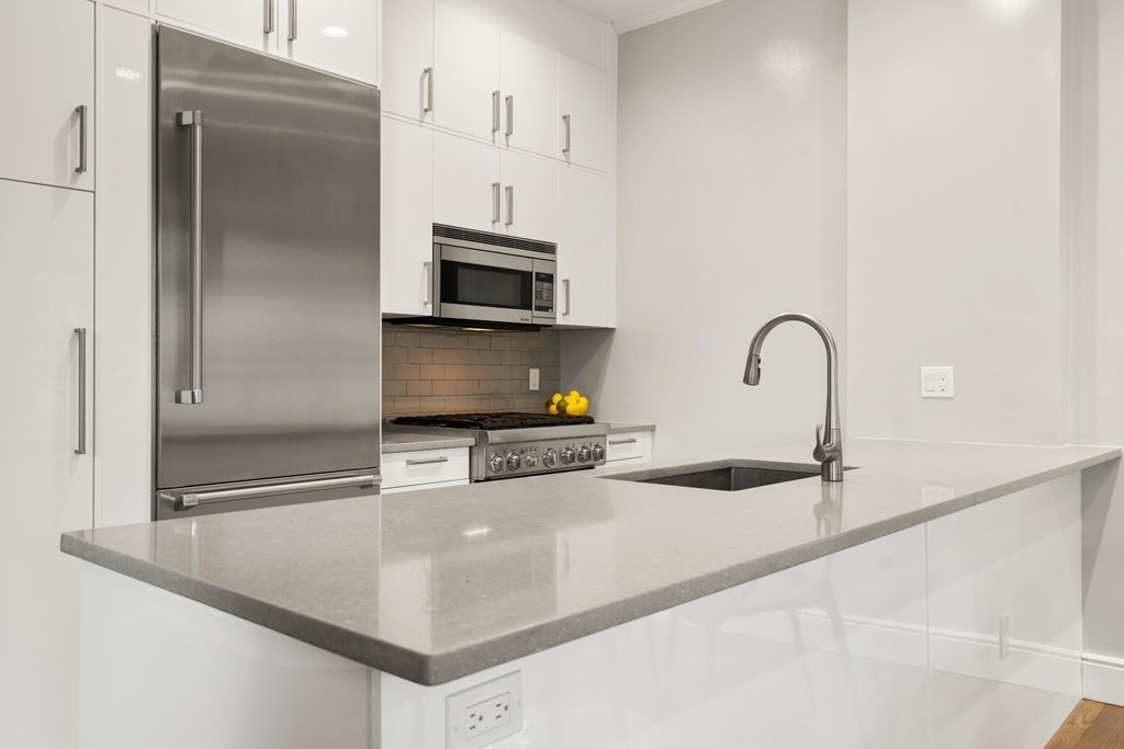 203 St Botolph Street, Unit 4 Boston, MA 02115 - Photo 4 of 26 a kitchen with stainless steel appliances a sink a stove and a refrigerator with white cabinets