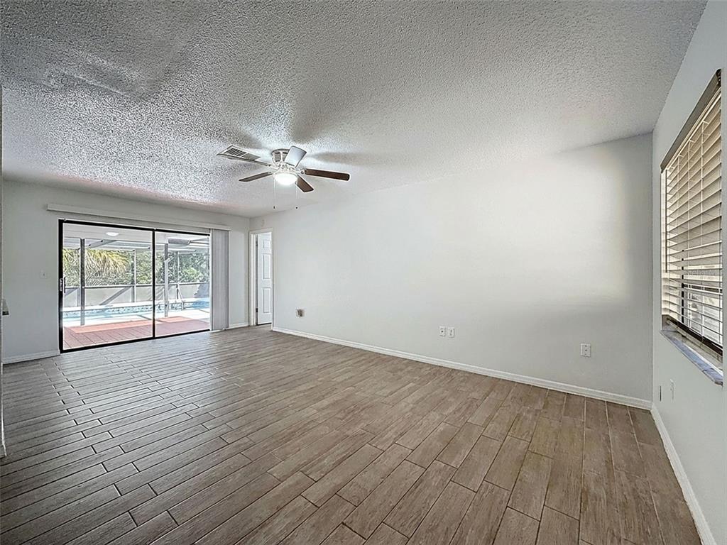 7410 Dundee Court Weeki Wachee, FL 34613 - Photo 11 of 33 an empty room with wooden floor fan and windows
