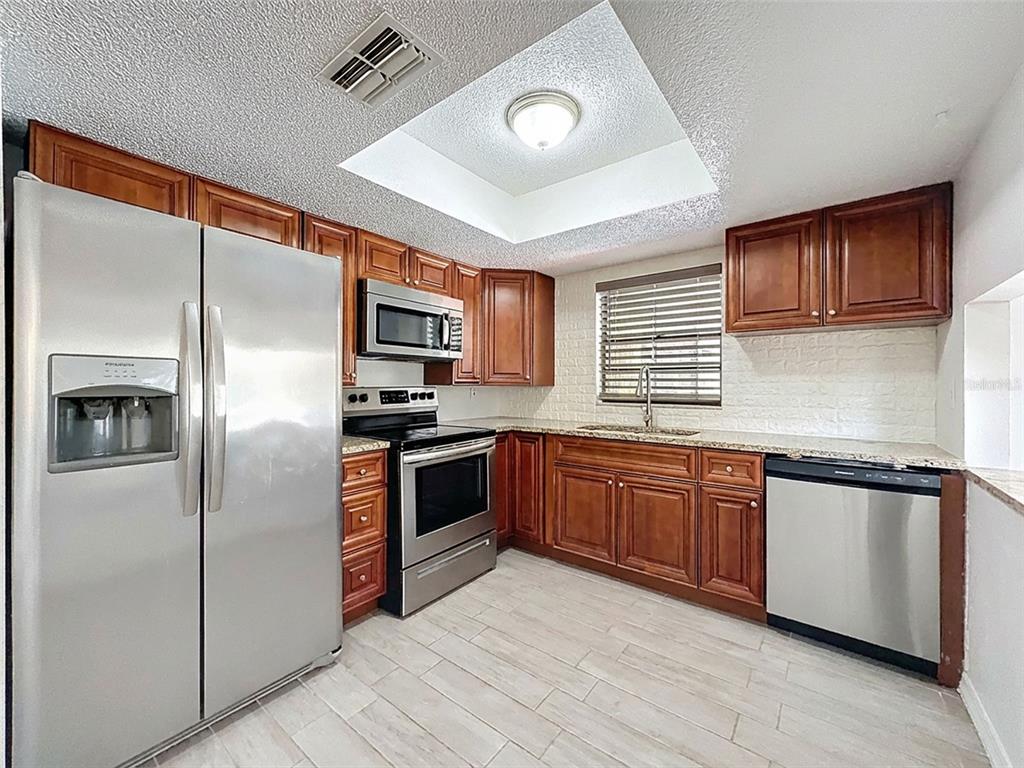 7410 Dundee Court Weeki Wachee, FL 34613 - Photo 14 of 33 a kitchen with granite countertop stainless steel appliances and refrigerator