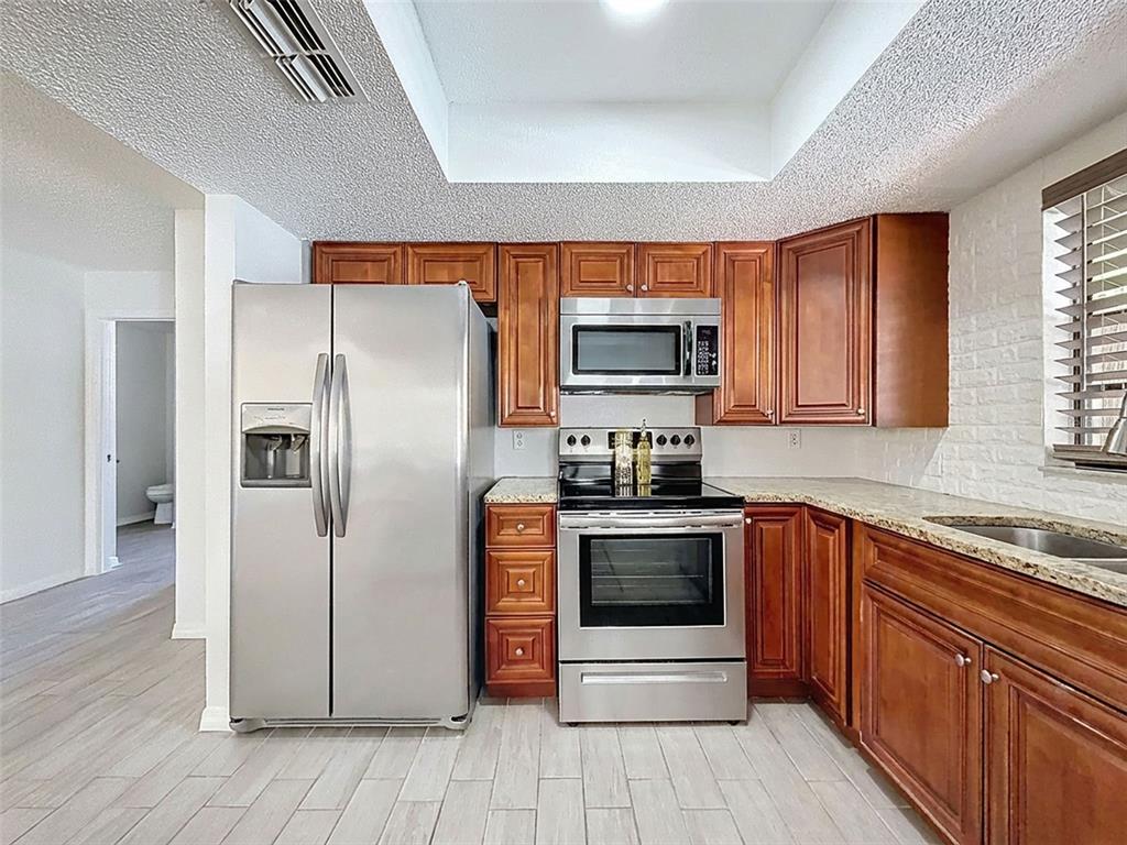 7410 Dundee Court Weeki Wachee, FL 34613 - Photo 15 of 33 a kitchen with stainless steel appliances granite countertop a refrigerator stove and sink
