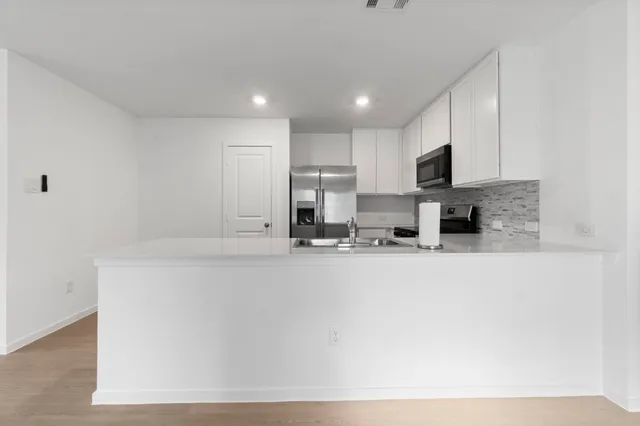 a kitchen with granite countertop a refrigerator and a stove top oven