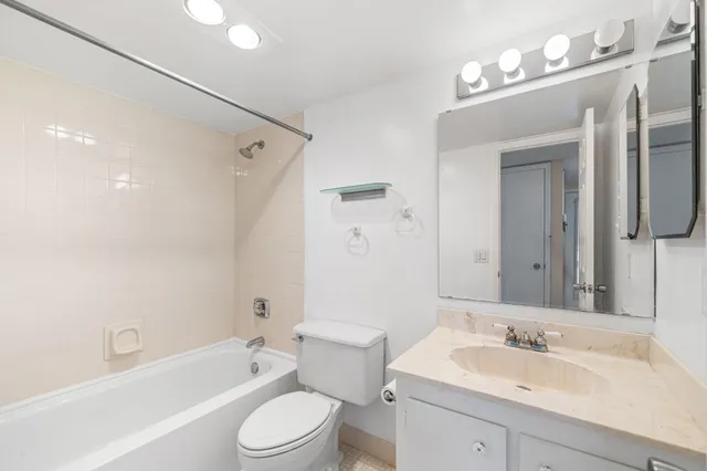 a bathroom with a toilet a sink a mirror a bathtub and vanity