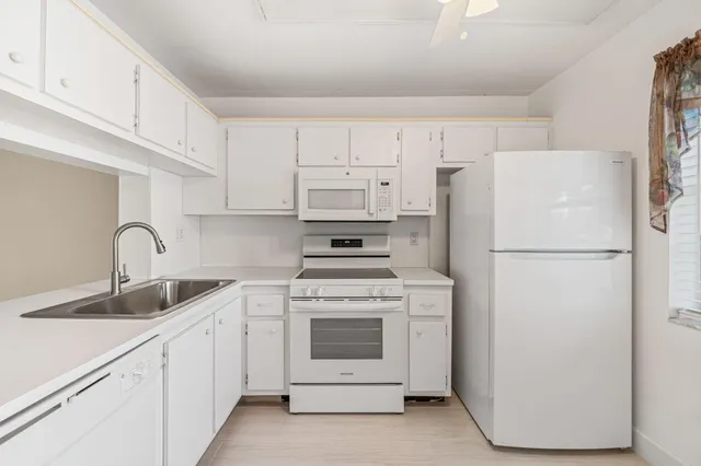 a kitchen with white cabinets and white stainless steel appliances and refrigerator