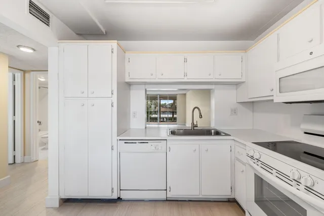 a kitchen with white cabinets and sink