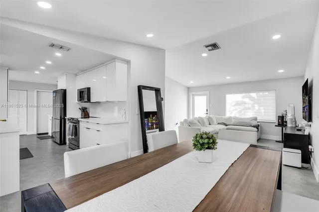 a large kitchen with kitchen island a refrigerator a stove a sink a dining table and chairs