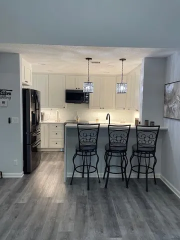 a kitchen with stainless steel appliances a table chairs refrigerator and a sink
