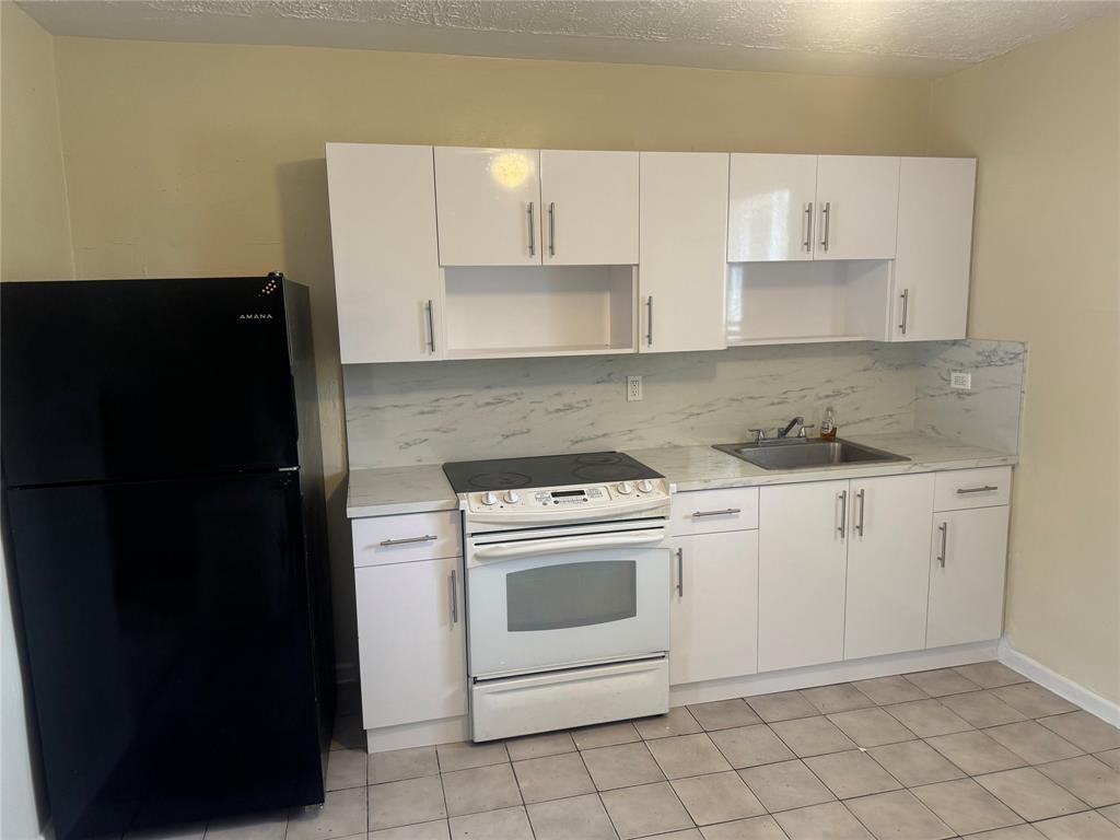 2986 Northwest 91st Street Miami, FL 33147 - Photo 16 of 40 a kitchen with white cabinets and black appliances