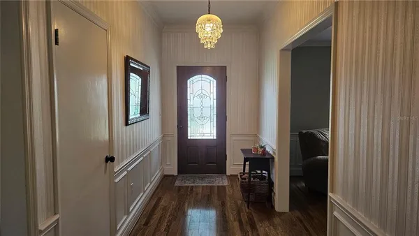 a view of a hallway with wooden floor and a chandelier